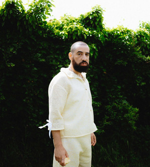 Daoud vue de trois-quart dans un jardin, bouche entrouverte, une seule dent apparente