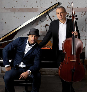 Devant un piano, Roberto Fonseca assis et portant un chapeau sur la t&ecirc;te, et Vincent Sega debout tenant son violoncelle