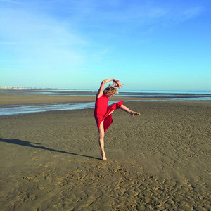 La danseuse &Eacute;lisabeth Schwarz performant au milieu d'une plage, en robe rouge