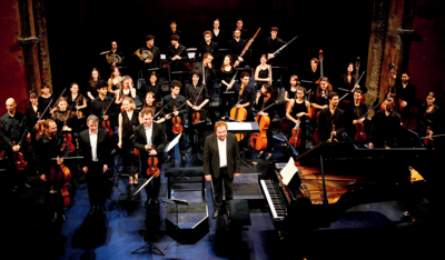 Vue de l'orchestre Ostinato sur sc&egrave;ne en tenue de concert, le chef d'orchestre Jean-Fran&ccedil;ois Heisser saluant le public au premier plan