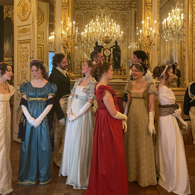 Femmes en tenues de bal color&eacute;es, de style Empire, sous un lustre illumin&eacute;