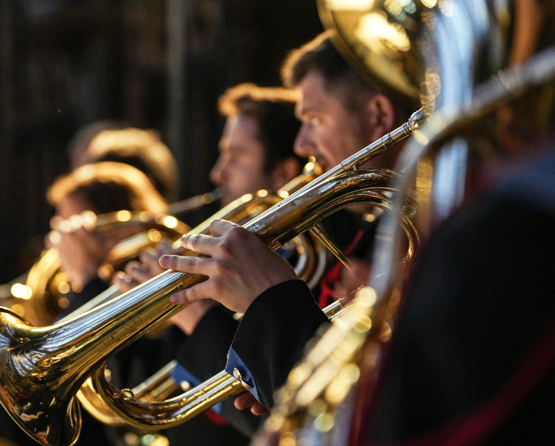 Zoom sur les musiciens de Batterie-Fanfare, l'un au premier plan jouant du trombone